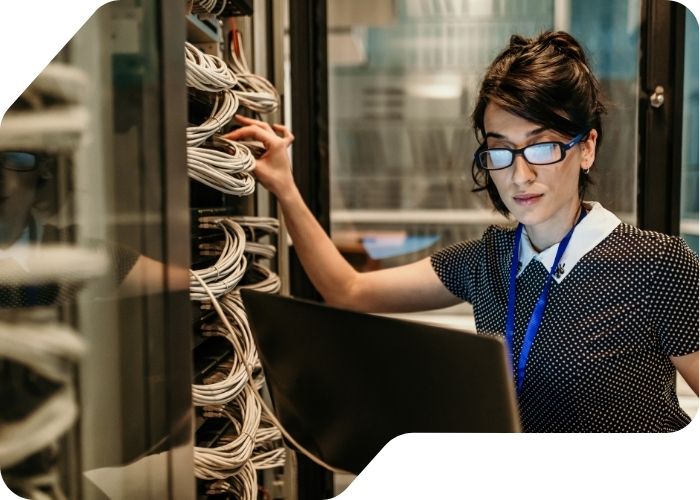 A woman wearing glasses is focused on her work at a computer