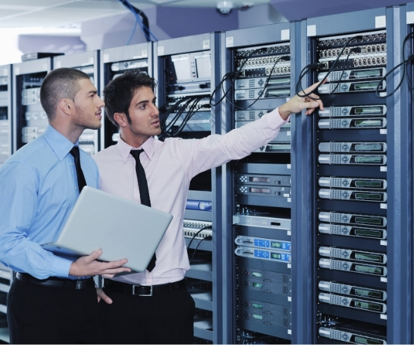 Two men in business suits examining server equipment in a data center